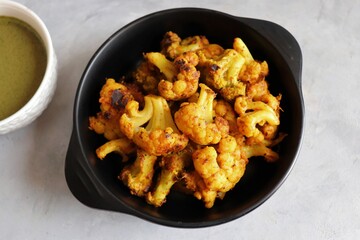 Gobi or Gobhi Tandoori. Masala Roasted cauliflower is a popular Indian vegetarian starter dish served with mint and coriander chutney. copy space.