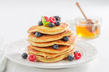 Sweet and homemade american pancakes with berries and honey