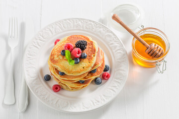 Homemade and sweet american pancakes with honey and berries.