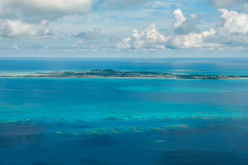 Incredible view of the island of Kohama surrounded by deep turquoise blue, full of corals seen from an airplane.