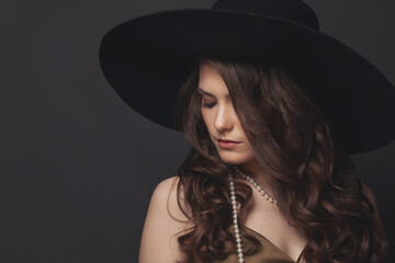 Portrait of young brunette model woman in black hat