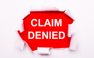 Torn white paper lies on a red background. On red, the text is white CLAIM DENIED