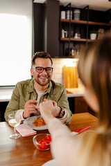 Smiling young couple having romantic lunch at home.