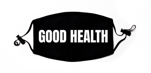 Black medical face mask on a light background with the inscription GOOD HEALTH. Disease prevention. Medical concept