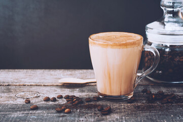 Cup of coffee with milk or cappuccino latte with can of coffee beans on dark wooden background