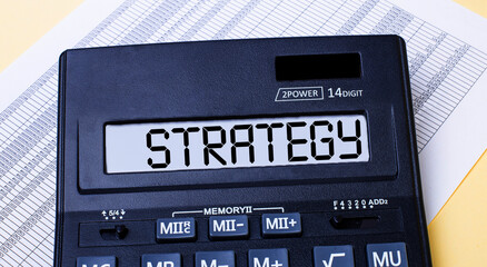 A calculator labeled STRATEGY is on the table near the report. Financial concept