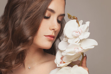 Portrait of beautiful young woman with white orchid flowers