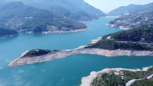An island in a reservoir in the mountains on the background of turquoise water - drone view