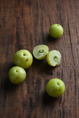Few fresh Indian gooseberries or Amlas placed on wooden background along with a sliced one. Gooseberries are full of vitamin C and natural goodness.