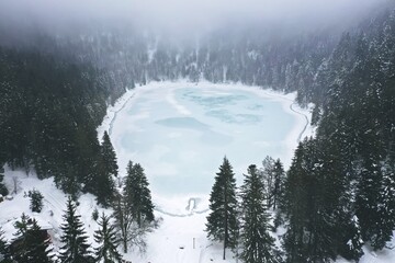 The frozen Lac des Corbeaux under the clouds, La Bresse, Vosges. France - Powered by Adobe
