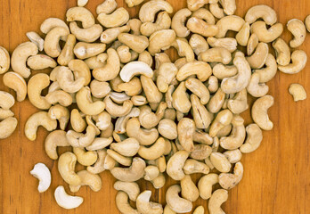 Raw cashew on wooden background. Natural organic nut kernel. Protein superfood or healthy snack. Cashew pile scattered on white table top view. Whole cashew package design. Healthy eating banner