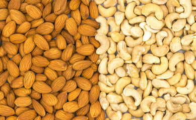 Cashew and almond texture on white background. Natural organic nut kernel. Protein superfood or healthy snack. Nuts pile scattered on white table top view. Granola package design. Healthy eating