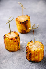 grilled corn on a skewer closeup on concrete background. corn with butter and salt top view