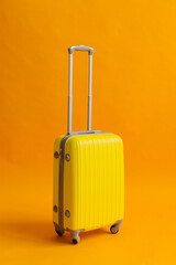 yellow plastic suitcase on a yellow background. travel suitcase