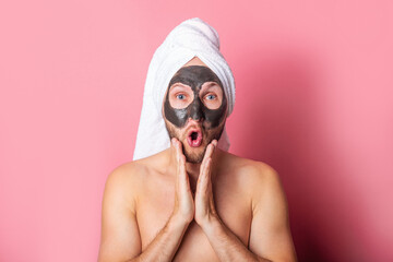 surprised young man with cosmetic mask on his face on pink background. Care, cleaning