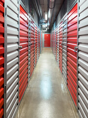 Storage corridor warehouse. Red and gray metal doors with locks. Organizing, storage concept. Self...