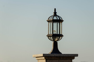 Ornate brass outdoor lantern flood light on top of a marble pillar