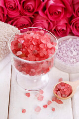 Glass bowl with red sea salt. Pink roses in the background.