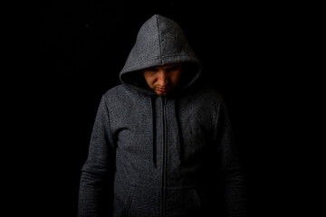 Fototapeta na wymiar Man in a hood and a hoodie on a dark background