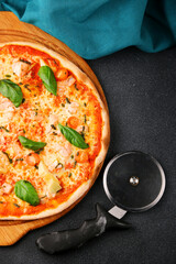 seafood pizza with shrimp and tomatoes on dark background top and pizza knife