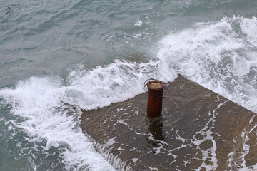 Dock Cleat On A Cement Platform. Copy Space. Sea waves crashing platform. Stock Image