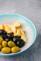 green and black olives closeup. Charcuterie plate on concrete backdrop or table with olives