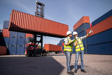 Logistics engineer and inspector working and discuss in shipping container in commercial transport...
