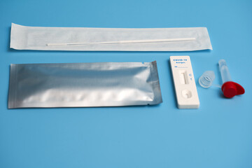 Antigen test also corona rapid test with test cassette, cotton swab and sample tube on a blue surface. Side view.