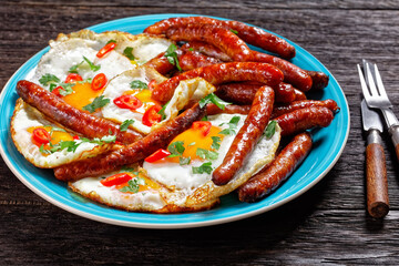 sausages with fried eggs on a plate, top view