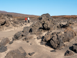 Volcanic rock road to Mutnovsky volcano. People near igneous stones after a volcanic eruption...