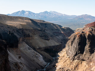 Obraz premium View of the Opasny canyon near the Mutnovsky volcano. Tourists stand near the edge of the canyon and admire incredible views of the volcanoes. Kamchatka Peninsula, Russia.