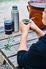 Vertical photo of the a Latin woman drinking mate grass and enjoying a day in the countryside