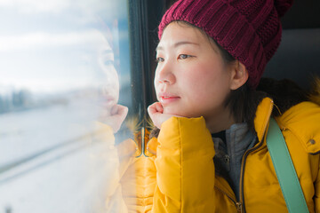 train travel getaway - young happy and beautiful Asian Korean woman enjoying snow landscape through...