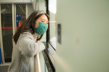 train travel in times of covid19 - young happy and cute Asian Korean woman in  face mask traveling on railcar looking landscape through the window enjoying holiday getaway
