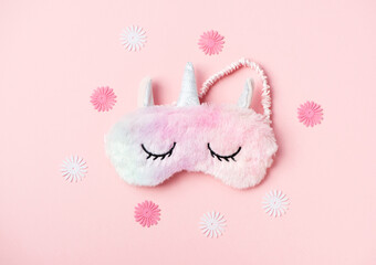 Fluffy fur sleeping eye mask unicorn on pink paper background. Top view, flat lay. Concept relaxation and sweet dreams
