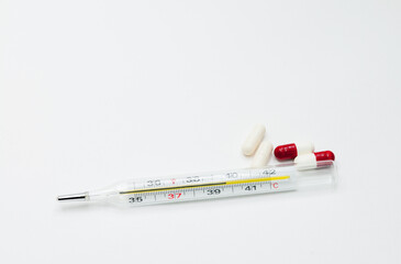 medical mercury thermometer with tablets on a white background