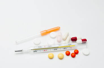 medical mercury thermometer with tablets on a white background