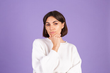Young brunette in white casual sweater isolated on purple background thinking worried about a question, concerned and nervous