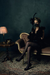 Fototapeta na wymiar Seductive young woman with a black boa and a mask in retro boudo