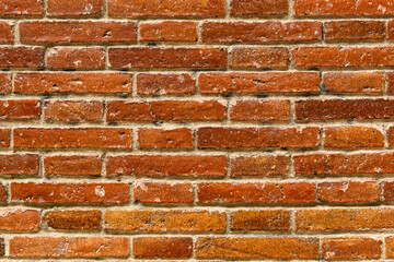 Old red brick background with fired enamel. Wall made of ceramic transom or crossbar bricks. Weathered Stained Old Brick Wall