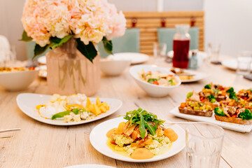 serving table with bouquet of pink flowers, appetizers and salads for holiday. 