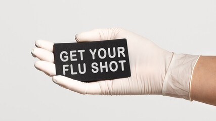 Closeup of the hand in a white sterile glove holding a card with words - Get Your Flu Shot