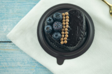 Fresh delicious chocolate cake heart shape decor with berries on plastic box placed on wooden table