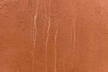 Red colored plastered wall with white stains. Grain textured background of brick color.
