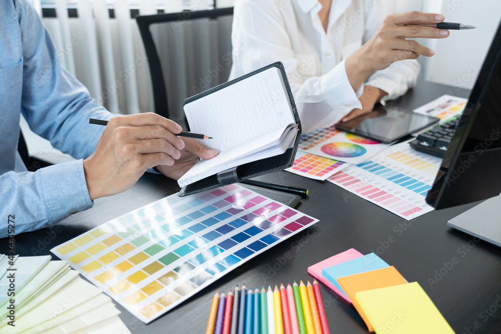 Poster graphic designer team working on web design using color swatches editing artwork using tablet and a 