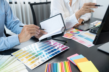 graphic designer team working on web design using color swatches editing artwork using tablet and a...