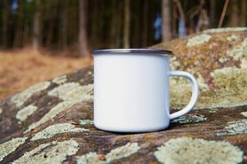 White enamel mug mockup, vintage campfire cup for design presentation, autumn forest.