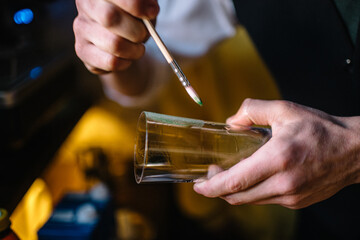 Bartender decorating glass with wasabi icing.