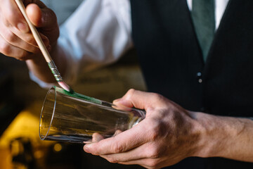 Bartender decorating glass with wasabi icing.