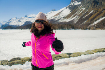 young Chinese woman enjoying amazing snowy landscape view - happy and beautiful Asian girl playful in front of frozen lake and snow mountains during Swiss Alps holiday